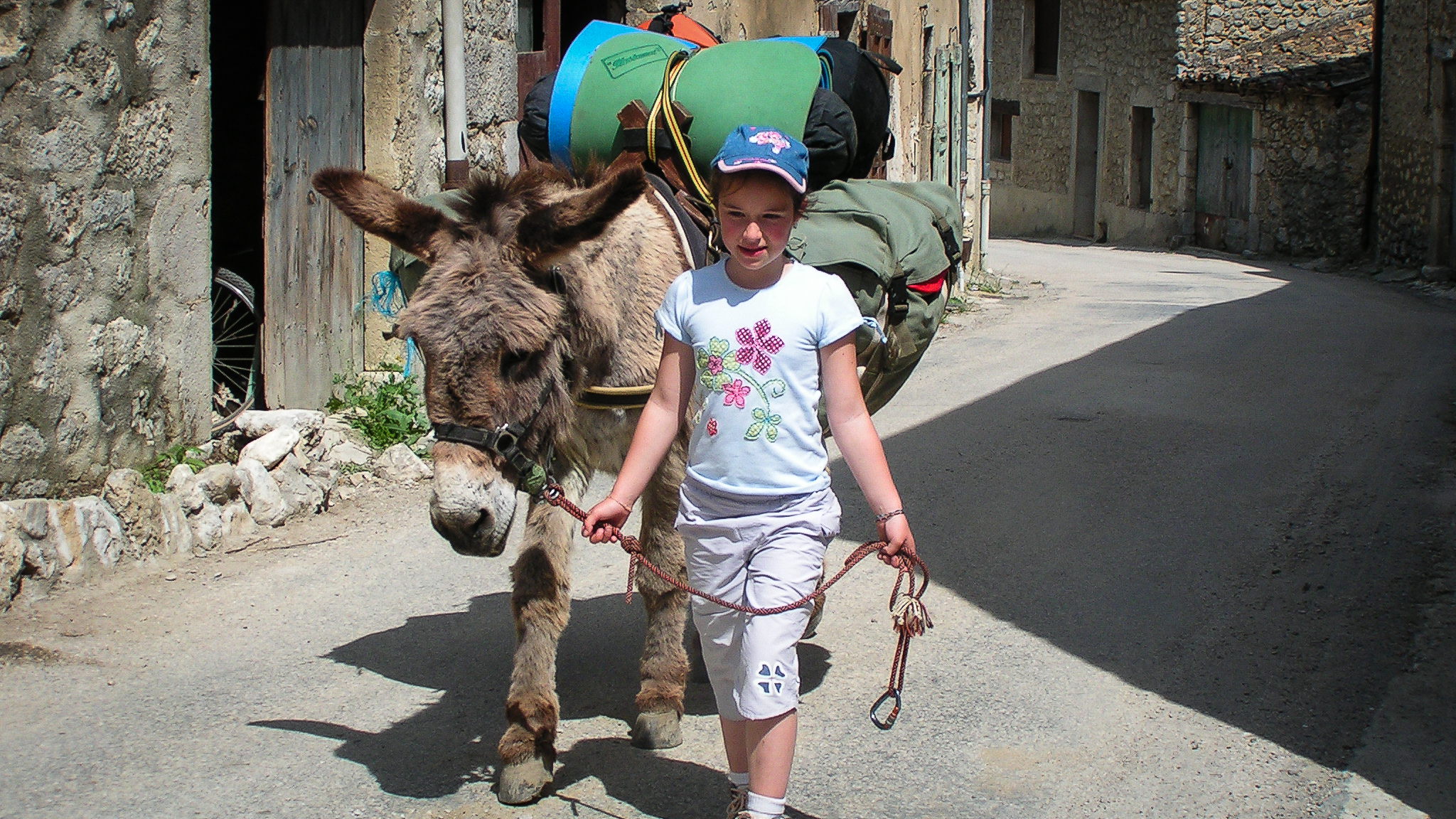 Traversée de village lors d'une rando en famille avec des ânes