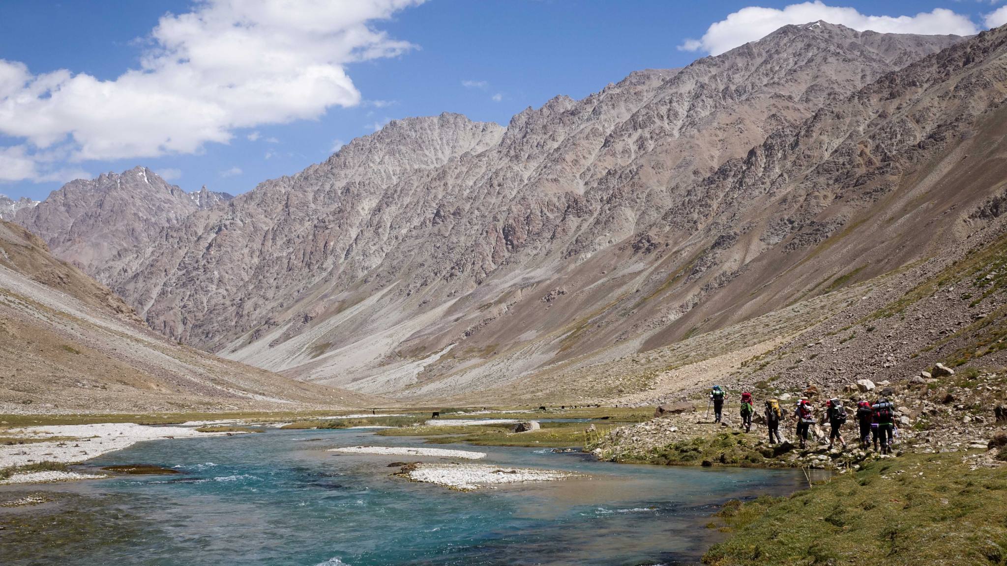 trekkeur le long d'une riviere dans des montagnes arides