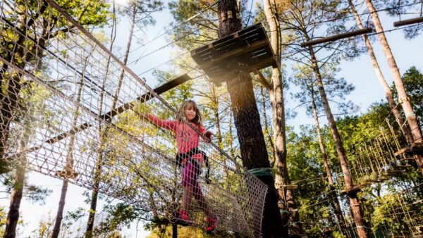 fillette randonnant dans les arbres dans un accrobranche