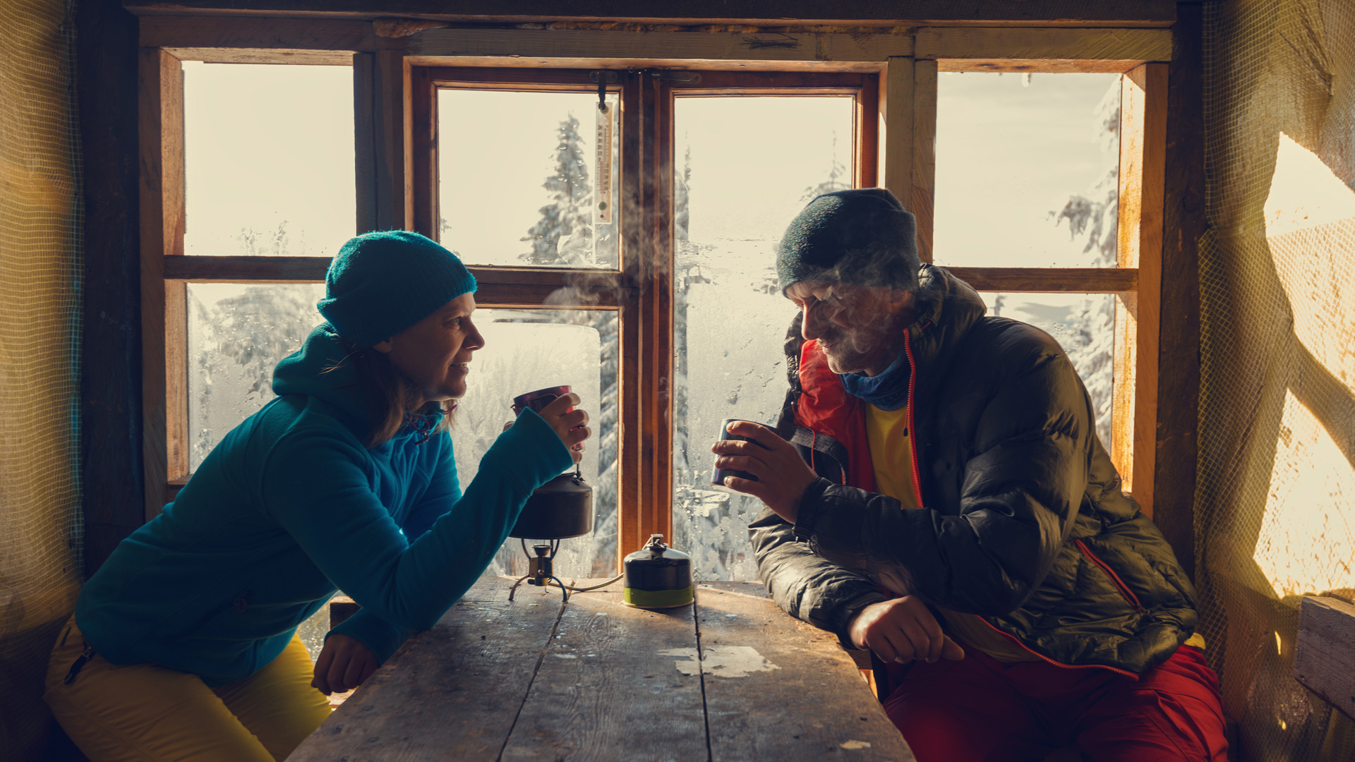2 randonneurs buvant une boisson chaude dans une cabane rustique du Vercors